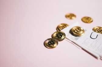 Close-up of Bitcoin coins and cash receipts on a soft pink background.