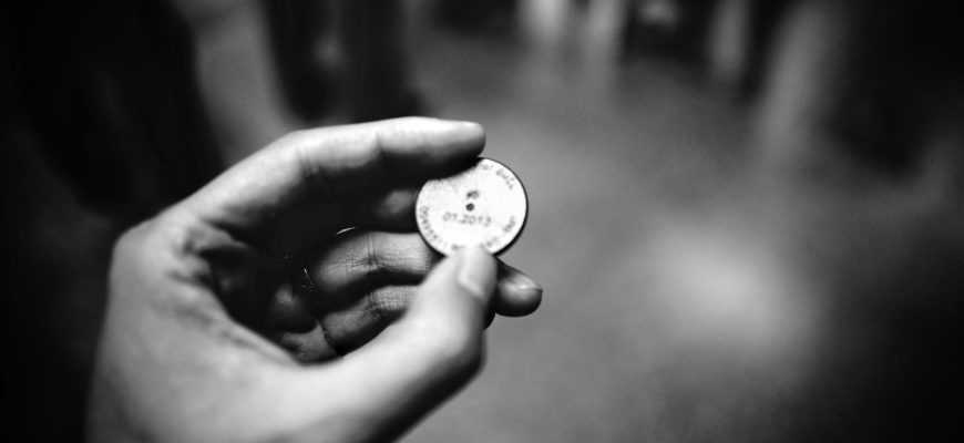 grayscale photography of person holding coin