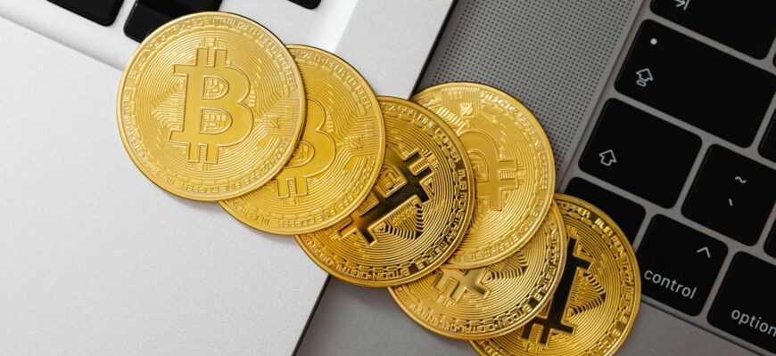 Golden Bitcoin coins spread across laptop keyboards showcasing digital currency and finance.