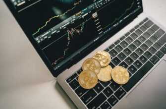 Golden bitcoin coins placed on a laptop keyboard with trading chart displayed on the screen.