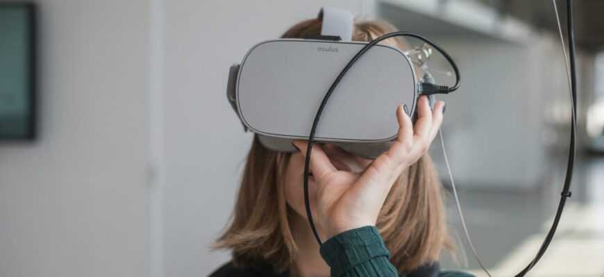 woman in black sweater holding white and black vr goggles
